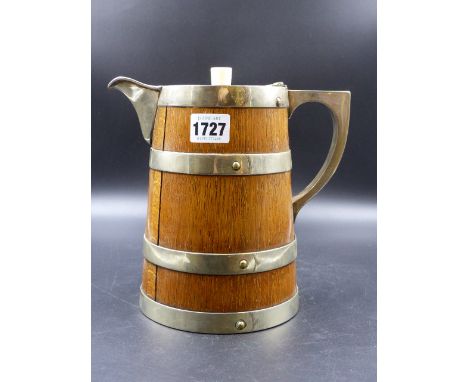 AN ELECTROPLATE COOPERED OAK JUG, THE CRESTED HINGED LID OVER A WHITE CERAMIC LINED INTERIOR.   H.21.5cms.