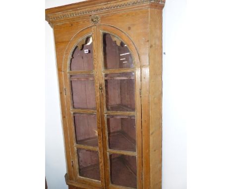 A 19th.C.PINE FLOOR STANDING CORNER CABINET WITH A PAIR OF ARCH TOP GLAZED DOORS ENCLOSING SHELVES OVER A SINGLE DOOR TO BASE