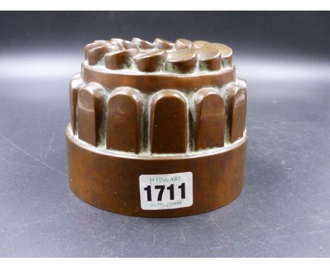 A 19th.C.COPPER CROWN MOULD, THE TOP WITH A CIRCLE OF CYLINDRICAL SHAPE STEPPED ABOVE A BAND OF ROUND ARCH TABLETS AND THE FL