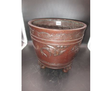 A JAPANESE BRONZE TRIPOD PLANTER, THE EXTERIOR CAST IN RELIEF WITH LONG TAILED BIRDS FLYING ABOUT CHERRY TREES, SHISHI MASKS 