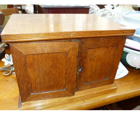 AN EDWARDIAN OAK COIN COLLECTOR'S CABINET WITH PANEL DOORS ENCLOSING NINE COIN SLIDES.   36 x 27 x H.25cms