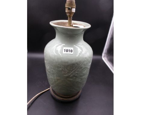 A CHINESE CELADON VASE ON A WOODEN STAND FITTED AS A LAMP. H.32.5cms.