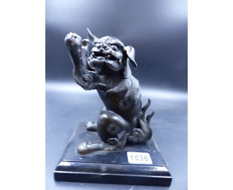 AN ORIENTAL BRONZE FIGURE OF A SEATED FOO LION WITH UPRAISED PAWS.   H.17cms.