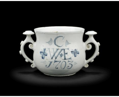 A rare English delftware posset cup, dated 1703Probably London, of bellied form, the unusual bossed scrolled handles with pro