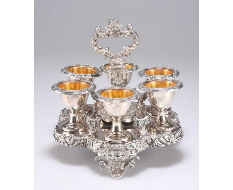 AN OLD SHEFFIELD PLATE EGG CRUET AND SIX CUPS, CIRCA 1835 with flower, leaf and scroll chased borders, central handle, on thr