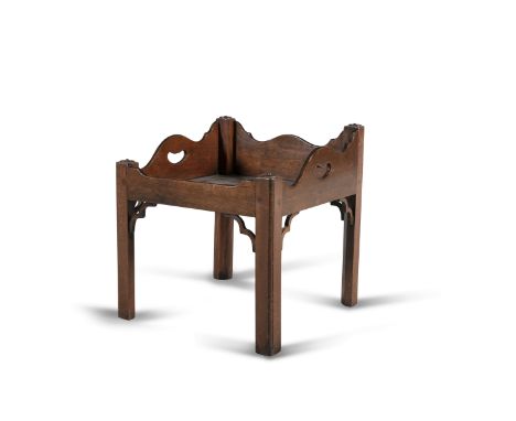 A MAHOGANY TRAY ON STAND, the shaped sides pierced with carrying handles, on chamfered supports (adapted from a bedside commo