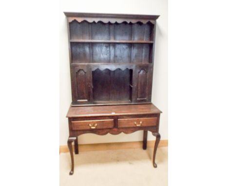 A Georgian style oak dresser with shelf and cabinet back, standing on table style base fitted two draws on cabriole legs 