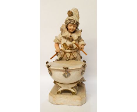 A terracotta figure of a young boy dressed as a clown playing a large kettle drum standing on an octagonal base, overall heig