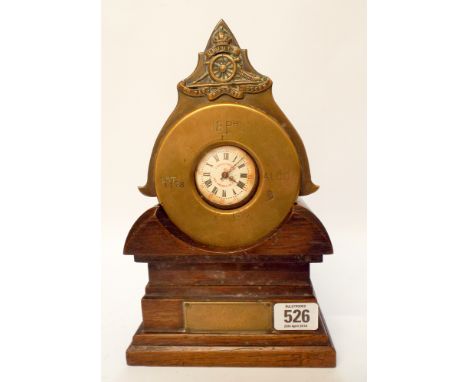 A piece of First World War trench art in the form of a mantel clock made from the end of a shell case on an oak base with a b