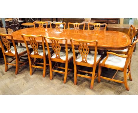 A large reproduction Georgian style yew wood extending dining table with two extra leaves standing on twin tripod bases, toge