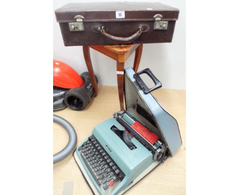 An old small brown leather suitcase, a typewriter and a three legged musical sewing box 