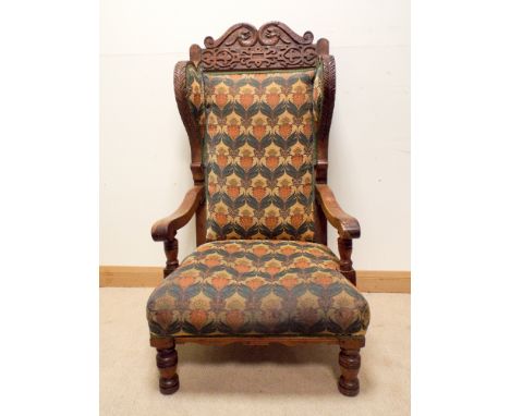 A large Edwardian carved oak wing backed elbow chair with tapestry upholstered seat and back 