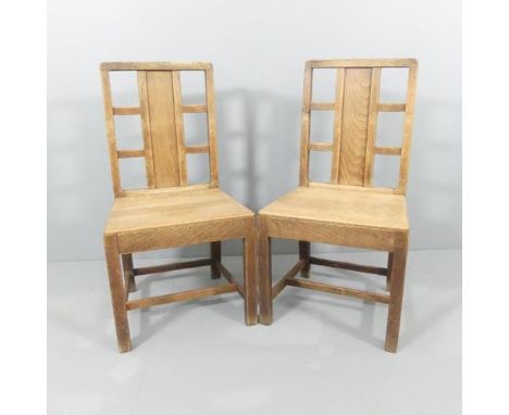 A pair of Arts and Crafts oak hall chairs with panel and lattice back in the manner of Heals.