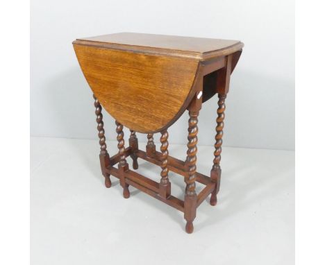 An early 20th century oval oak gate-leg drop-leaf table with barley twist supports. 63x73x27cm (extending to 87cm).