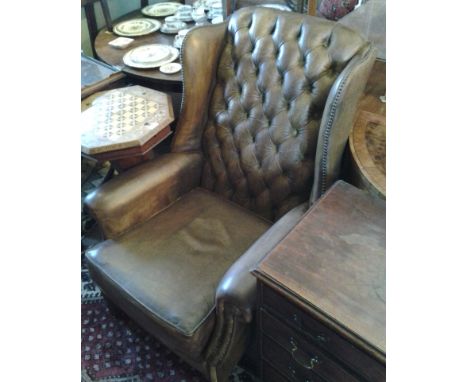 A Leather Upholstered Button Backed Wingback Armchair with scroll arms raised upon square legs
