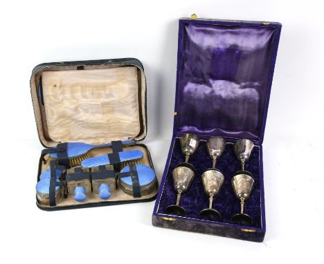 Engine turned and blue enamelled travel dressing set, with brushes and bottles, in a leather lined case with inscribed label,