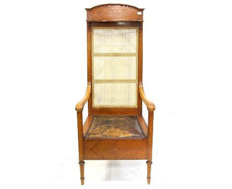 Edwardian quarter veneered satinwood commode chair with high cane back with hinged shelf over a leather hinged seat on reeded