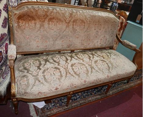 An early 20th century French walnut sofa, parcel gilt, with floral damask upholstery, raised on reeded tapered legs 