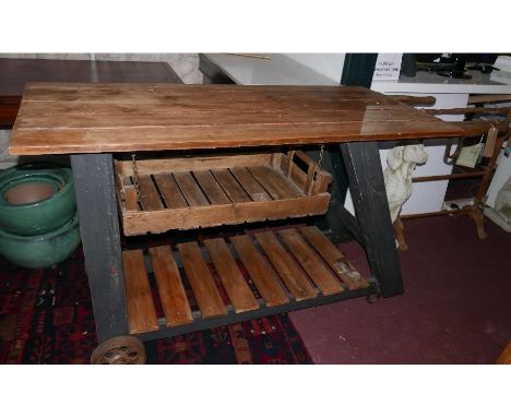 A large industrial design kitchen table/trolley, with planked top over hanging tray and slatted undertier shelf, raised on wh