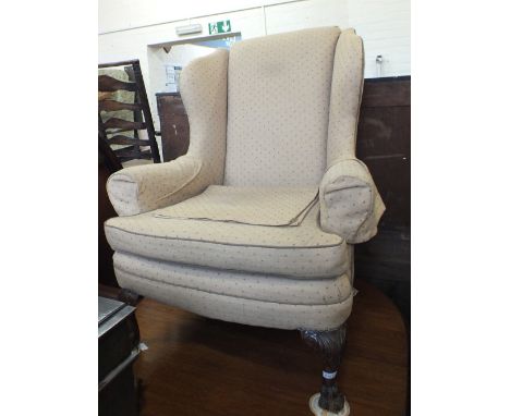 A Georgian style armchair in beige upholstery with carved front pad feet and matching foot stool