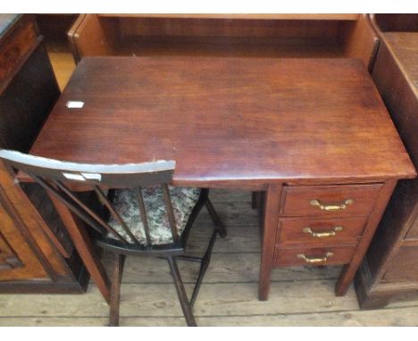 A stained oak three drawer desk with a folding leaf and an upholstered stick back chair