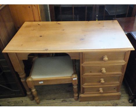 A light pine desk with four drawers and a pine upholstered stool