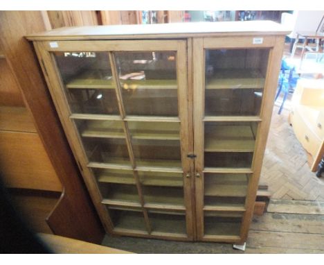 A large light oak glazed two door cupboard with adjustable shelves