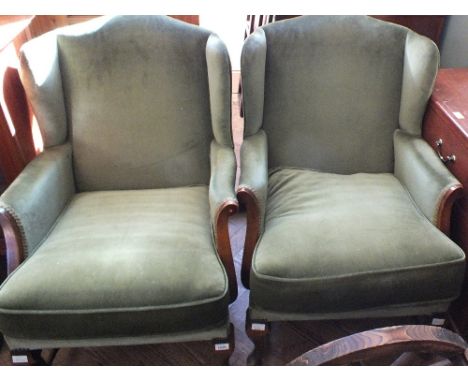 A pair of vintage wingback armchairs with pale green velour upholstery