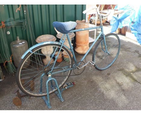 A vintage blue painted bicycle with stand to use as an exercise bike