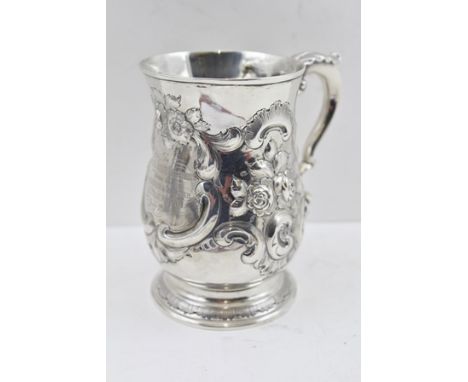 A GEORGE III SILVER TANKARD of baluster form, repousse floral decoration, the scrolling handle with acanthus leaf thumb piece