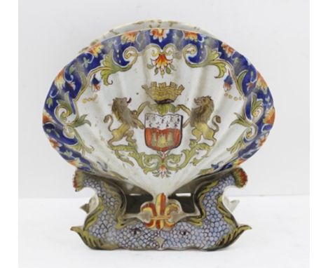 A FRENCH FAIENCE VASE of scallop shell form, hand-painted with harvester sharpening his scythe to one side and a coat of arms