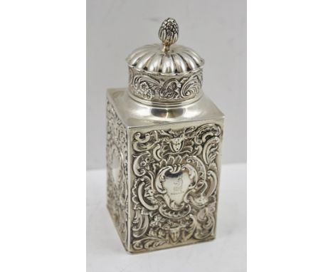 A LATE VICTORIAN SILVER TEAPOY of square form with repousse decoration, engraved crest to one of the four cartouche, fitted f