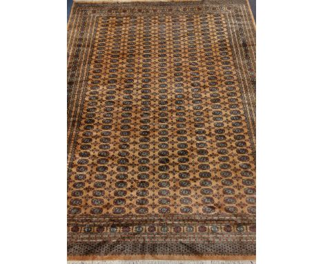 Fine quality Persian Bokhara design rug carpet, repeating guls on pale gold ground, 405cm x 310cm Condition Report Click here