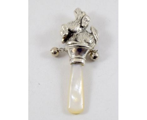 a silver babies rattle in the form of a dog with mother of pearl handle