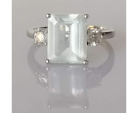 An aquamarine and diamond dress ring on a white gold setting, the emerald-cut aquamarine measuring 3.71 carats flanked by two