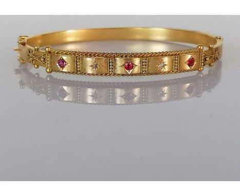 A late Victorian Etruscan-style ruby and diamond hinged gold bangle, interior 65mm W, hallmarked 9ct, Birmingham, 1900, 7.5g
