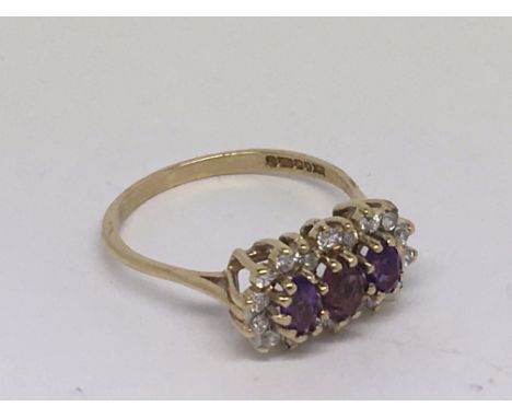 A amethyst triple cluster ring set in gold.  Size R