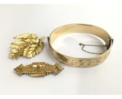 A 15ct gold bar brooch with decorative central flower, approximately 2.8 grams, a 9ct rolled gold bangle, approximately 29.2 