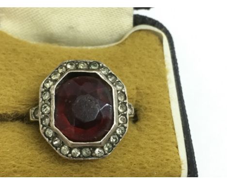 A 9ct gold ring set with octagonal red stone in white chip surround. Approx size M