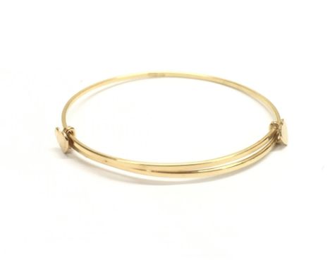 An 18ct gold childâ€™s bangle decorated with two hearts. Total weight approximately