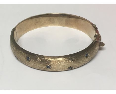 A 9ct Gold bangle set with blue Sapphires weight 22g.