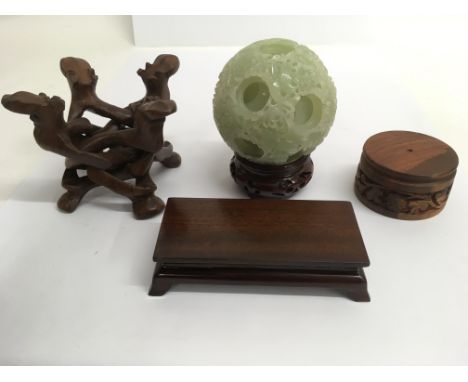 A Chinese jade type puzzle ball and three wood stands