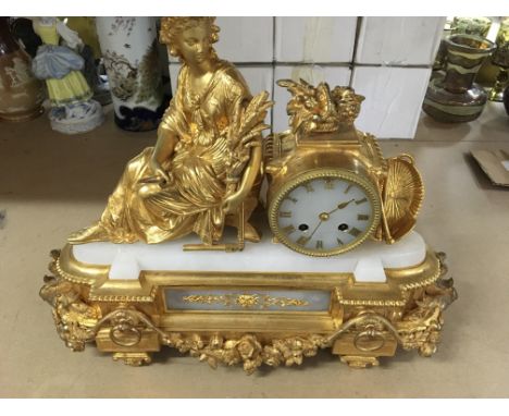 A 19 th century gilt mantel clock of classical form surmounted with a maiden the dial with Roman numerals maker W Ralps on a 