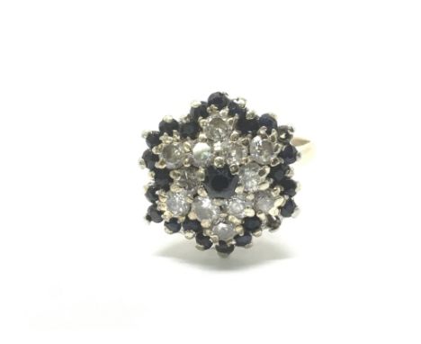 A 9ct gold cluster ring set with sapphires and diamonds with floral motif. Total weight approx 5.4 grams, ring size R.