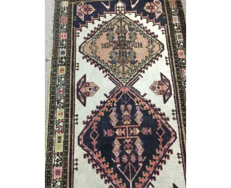 A Persian style runner with geometric pattern and a carpet with floral design red ground and repeat pattern boarder