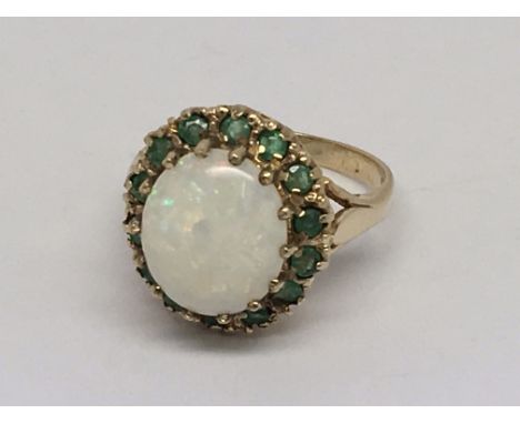 An opal and emerald cluster ring set in yellow gold.  Size N