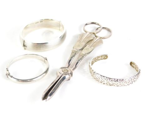 A silver bangle, partially engine turned, 7cm wide, two further bangles and a pair of grape scissors.  (4)