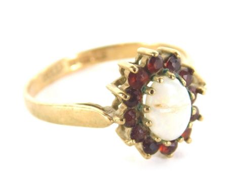 A 9ct gold dress ring, claw set with opal, in a floral arrangement of small red stones on a part pierced shank, marked 375, s