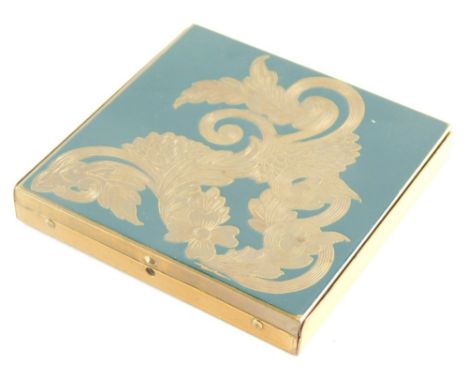 A 1960s gilt metal powder compact, decorated with flowers and scrolls on a black ground, 8.5cm wide. Provenance: sold with ce