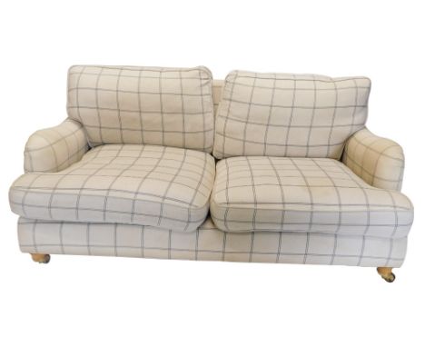 A Laura Ashley two seater sofa, upholstered in cream and grey chequed fabric, on turned legs with brass castors, 172cm wide. 